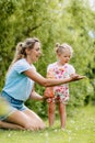 A little girl and her mother blow soap bubbles on a blurry background in a park or garden. A loving and happy family Royalty Free Stock Photo