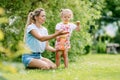 A little girl and her mother blow soap bubbles on a blurry background in a park or garden. A loving and happy family Royalty Free Stock Photo