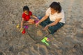 Little girl and her mother making a fort with sand on the beach, Alibag, Konkan, India. Royalty Free Stock Photo