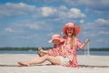 A little girl with her mother in matching beautiful sundresses plays in the sand on the beach. Stylish family look Royalty Free Stock Photo