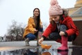 Little girl and her mother playing with paper boat near puddle outdoors Royalty Free Stock Photo