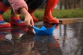 Little girl and her mother playing with paper boat near puddle outdoors, closeup Royalty Free Stock Photo