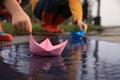 Little girl and her mother playing with paper boats near puddle outdoors, closeup Royalty Free Stock Photo