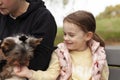 Little girl and her mother playing with a Yorkshire Terrier in the park Royalty Free Stock Photo