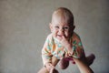 A little girl in her mother`s arms above her head smiles with a finger in her mouth Royalty Free Stock Photo