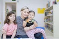 Little girl with her mother and sister in kindergarten