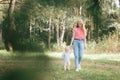 A little girl and her mother are walking along a forest path on a clear Royalty Free Stock Photo