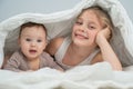 Little girl and her newborn brother hiding under the blanket. Royalty Free Stock Photo