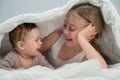 Little girl and her newborn brother hiding under the blanket. Royalty Free Stock Photo