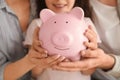 Little girl with her parents holding piggy bank, closeup. Money savings concept