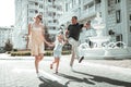 Little girl and her parents skipping along the street.