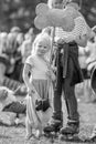 A little girl with her puppy in a sling holding a giant bone in the park at a dog show.