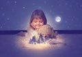 Little girl with her teddy bear, watching a enchanted forest  on the pages of an open magic book Royalty Free Stock Photo