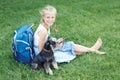 Little girl with his dog sitting on green grass and read e-book. Royalty Free Stock Photo