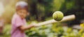 Little girl hitting tennis ball with baseball bat at park. batting practice. copy space