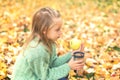 Little girl is holding apple and mug on autumn leaves in autumn park Royalty Free Stock Photo