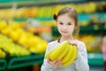 Little girl holding bananas in a food store Royalty Free Stock Photo