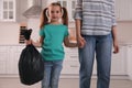 Little girl holding bin bag full of garbage in kitchen Royalty Free Stock Photo