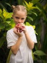 Little girl holding bunch of red grapes, Caucasian girl eating grape. Selected focus. Green tropical leaves background. Organic