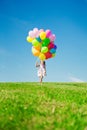 Little girl holding colorful balloons. Child playing on a green Royalty Free Stock Photo