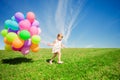 Little girl holding colorful balloons. Child playing on a green