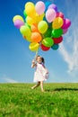 Little girl holding colorful balloons. Child playing on a green Royalty Free Stock Photo