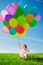 Little girl holding colorful balloons. Child playing on a green Royalty Free Stock Photo