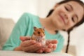 Little girl holding cute hamster at home, focus on hands