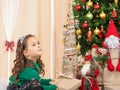 Little girl holding a gift in front of christmas tree Royalty Free Stock Photo