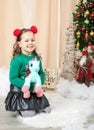 Little girl holding a unicorn in front of christmas tree Royalty Free Stock Photo