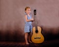 Little girl holding a guitar and showing a super sign with the second hand on a vintage background