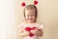 Little girl holding heart. Small heart shape pillow holding by little Caucasian girl smiling with innocence, at home