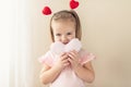 Little girl holding heart. Small heart shape pillow holding by little Caucasian girl smiling with innocence, at home