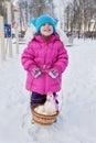 Little girl holding in her hands a basket with Easter eggs and a rooster, day of the winter on the street in the Park Royalty Free Stock Photo