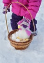 Little girl holding in her hands a basket with Easter eggs and a rooster, day of the winter on the street in the Park Royalty Free Stock Photo