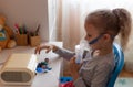 Little girl holding an inhaler mask sitting at table