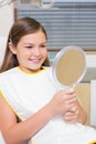 Little girl holding mirror in dentists chair Royalty Free Stock Photo