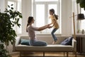 Little girl holding mommy hands and jumping on couch Royalty Free Stock Photo