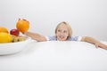 Little girl holding orange from fruit bowl at table Royalty Free Stock Photo