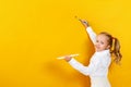 Little girl holding a palette and brush. A child is painting on a yellow empty wall