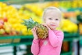 Little girl holding a pineapple in a food store Royalty Free Stock Photo