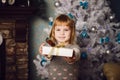 Little girl holding present near the christmas tree Royalty Free Stock Photo