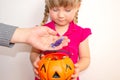 Little girl holding a pumpkin with candies in her hands, on Halloween. Grown-up people put candy to children in a pumpkin. Royalty Free Stock Photo
