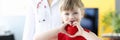 Little girl holding red toy heart in her hands in doctors office Royalty Free Stock Photo