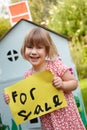 Little Girl Holding For Sale Sign Outside Play House Royalty Free Stock Photo