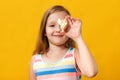 Little girl holding a seashell. Closeup baby in a summer dress on a yellow background