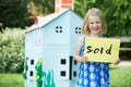 Little Girl Holding Sold Sign Outside Cardboard Playhouse Royalty Free Stock Photo