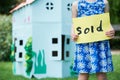 Little Girl Holding Sold Sign Outside Cardboard Playhouse Royalty Free Stock Photo