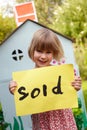 Little Girl Holding Sold Sign Outside Play House Royalty Free Stock Photo