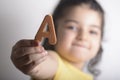 Little girl holding A spongy alphabet letter in right hand